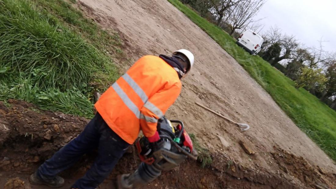 Compactage du remblai à la pilonneuse — opérateur en EPI sur chantier de génie civil